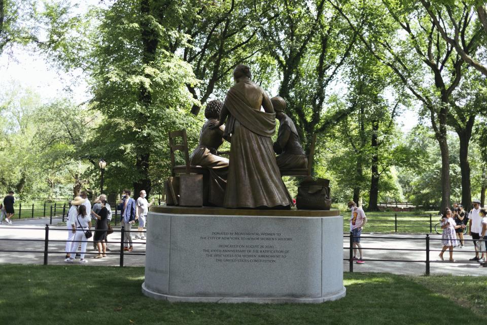 Visitors interact with the Women's Rights Pioneers statue in Central Park Wednesday, Aug. 26, 2020, in New York. The statue, created by sculptor Meredith Bergmann and featuring Sojourner Truth, Susan B. Anthony and Elizabeth Cady Stanton, is the first monument in the park honoring any female historical figures. (AP Photo/Kevin Hagen)