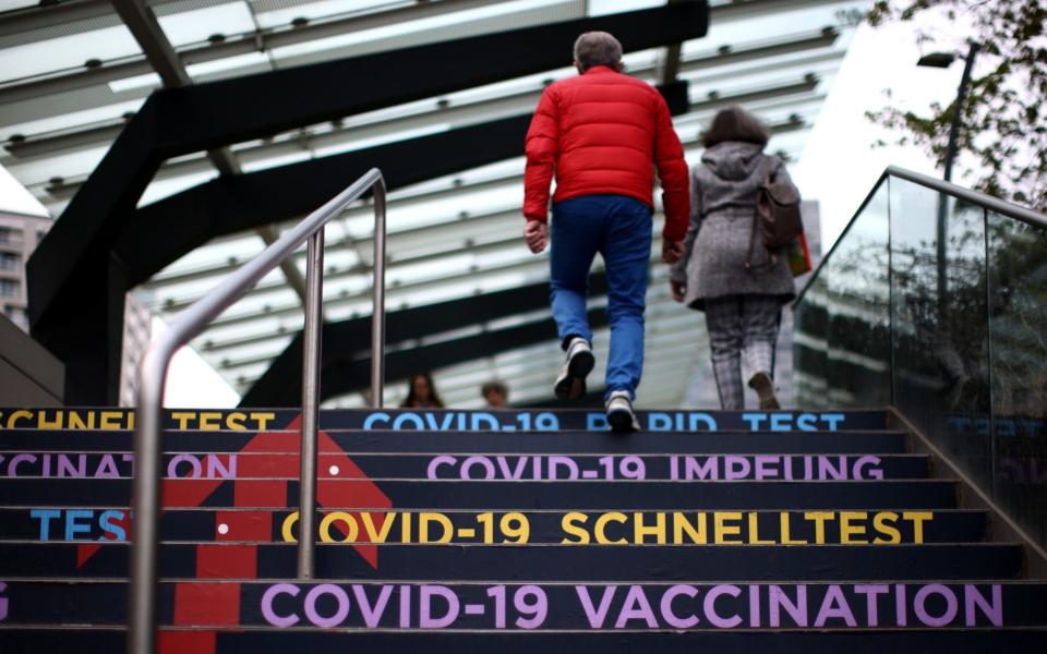 People walk towards the Covid-19 vaccine and test centre at Austria Center, which has been set up as a coronavirus disease mass vaccination centre, in Vienna, Austria  - LISI NIESNER / REUTERS