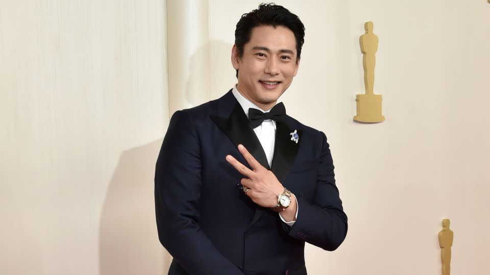 South Korean actor Teo Yoo wore a custom navy double-breasted Louis Vuitton suit. The “Past Lives” star finished off the look with a turtle pin honoring his late pet tortoise Momo, he told Variety on the red carpet. - Richard Shotwell/Invision/AP