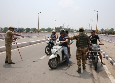 Indian security personnel stop residents during restrictions in Jammu