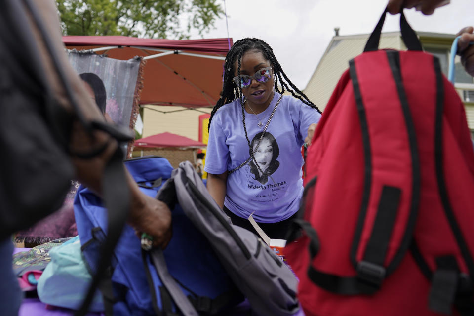 Nikiesha Thomas' sister Keeda Simpson wears a T-shirt with an image of her sister as she hands out donated school supplies during a Back To School Block Party in the Robinwood Community of Annapolis, Md., Sunday, Aug. 21, 2022. The block party was hosted by Beacon Light Seventh-day Adventist Church, and sponsored by the Nikiesha Thomas Memorial and Allstate Insurance. Nikiesha Thomas was shot and killed by her ex-boyfriend just days after filing for a protective order. (AP Photo/Carolyn Kaster)