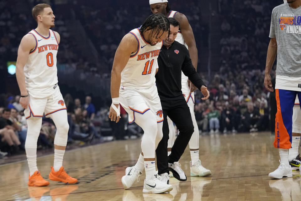 New York Knicks guard Jalen Brunson (11) is helped off the court after an injury in the first half of an NBA basketball game against the Cleveland Cavaliers, Sunday, March 3, 2024, in Cleveland. (AP Photo/Sue Ogrocki)