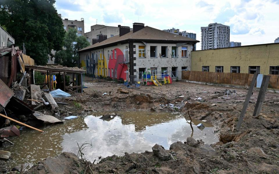 A photograph shows a crater filled with water caused by Russian missiles at a nursery school in Kyiv - SERGEIR SUPINSKY/AFP