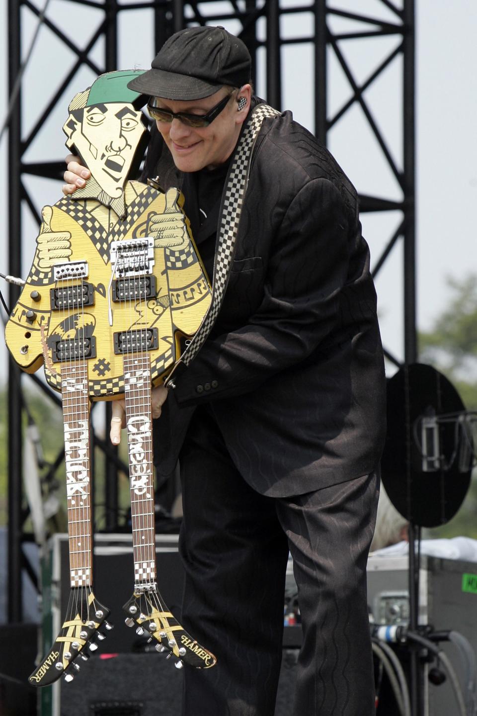 In this Aug. 4, 2007 file photo, Cheap Trick's Rick Nielsen holds his trademark guitar, "Uncle Dick" at the Virgin Festival in Baltimore. The guitar is among those featured in a book entitled "108 Rock Star Guitars" by photographer Lisa S. Johnson. (AP Photo/Jeff Christensen)