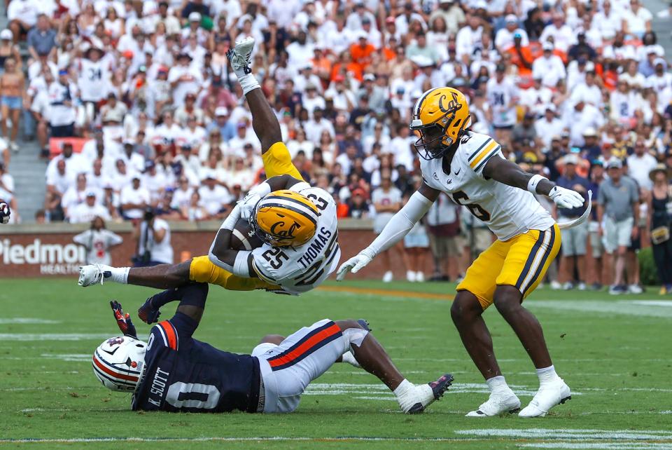 Sep 7, 2024; Auburn, Alabama, USA; California Golden Bears running back Jaivian Thomas (25) goes airborne after being tackled by Auburn Tigers cornerback Keionte Scott (0) during the first quarter at Jordan-Hare Stadium. Mandatory Credit: John Reed-Imagn Images