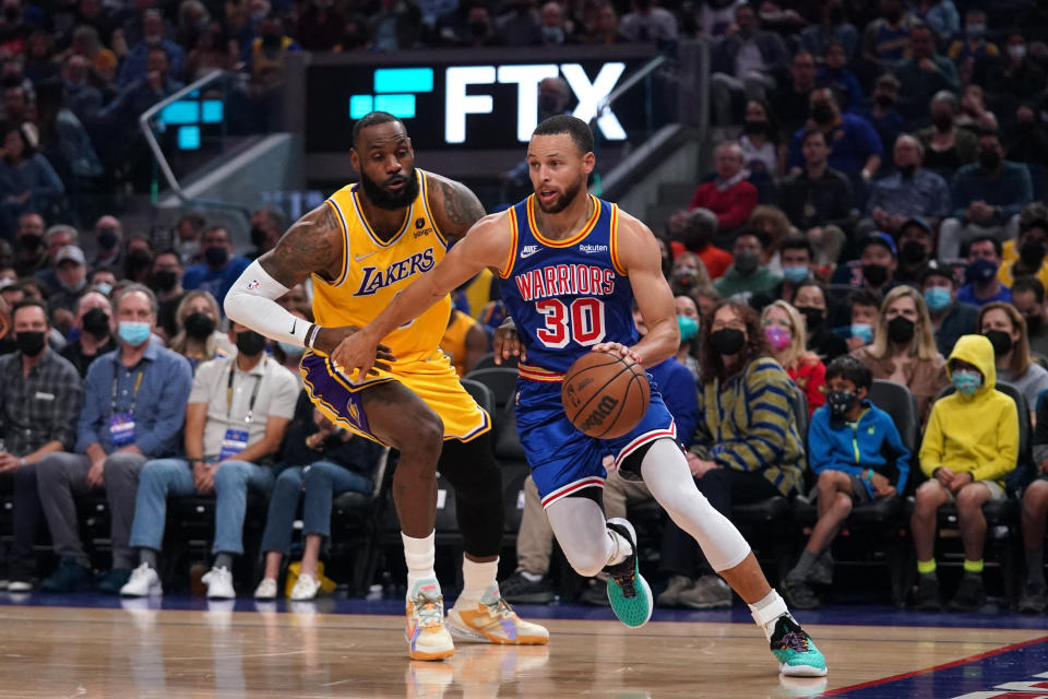 Feb 12, 2022; San Francisco, California, USA; Golden State Warriors guard Stephen Curry (30) dribbles past Los Angeles Lakers forward LeBron James (6) in the first quarter at the Chase Center. Mandatory Credit: Cary Edmondson-USA TODAY Sports