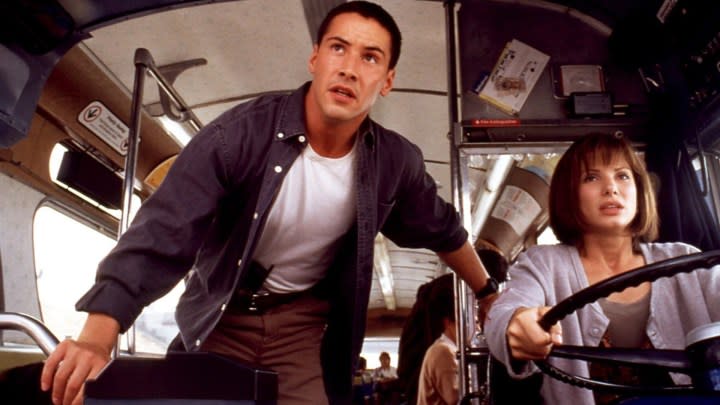 Keanu Reeves stands by Sandra Bullock as she drives a bus in a scene from the movie Speed