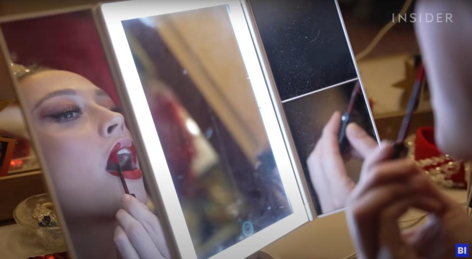 A Moulin Rouge dancer applies make up.