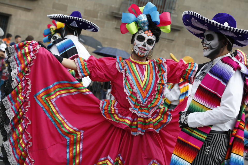 Performers in costume attend a Day of the Dead parade in Mexico City, Sunday, Oct. 27, 2019. The parade on Sunday marks the fourth consecutive year that the city has borrowed props from the opening scene of the James Bond film, "Spectre," in which Daniel Craig's title character dons a skull mask as he makes his way through a crowd of revelers. (AP Photo/Ginnette Riquelme)