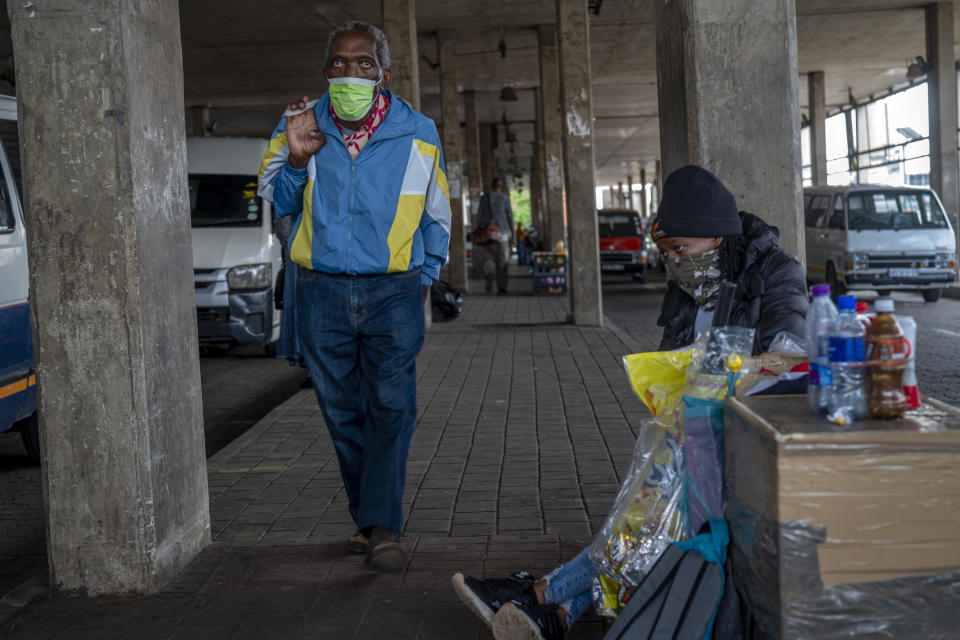 A woman selling snacks, sits at the Baragwanath taxi rank in Soweto, South Africa, Thursday Dec. 2, 2021. South Africa launched an accelerated vaccination campaign to combat a dramatic rise in confirmed cases of COVID-19 a week after the omicron variant was detected in the country. (AP Photo/Jerome Delay)