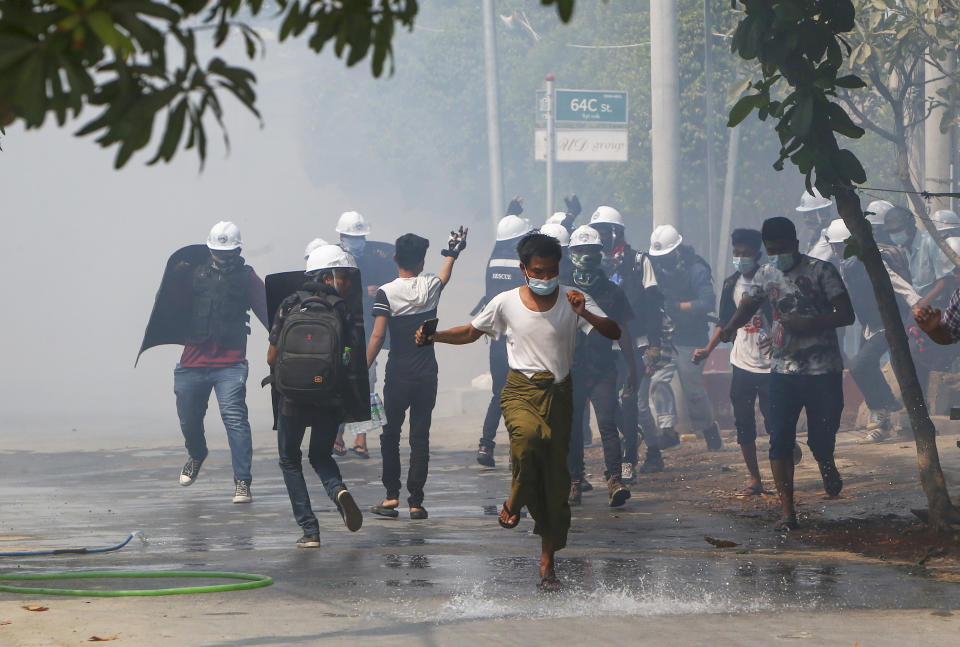 Anti-coup protesters with makeshift shields provide cover to others to retreat after releasing fire extinguishers towards armed policemen and soldiers in Mandalay, Myanmar, Wednesday, March 10, 2021. Protesters against the military takeover in Myanmar carried homemade shields and moved with more caution and agility Tuesday, adapting their tactics to the escalating violence from security forces not reluctant to use lethal force to break up crowds. (AP Photo)