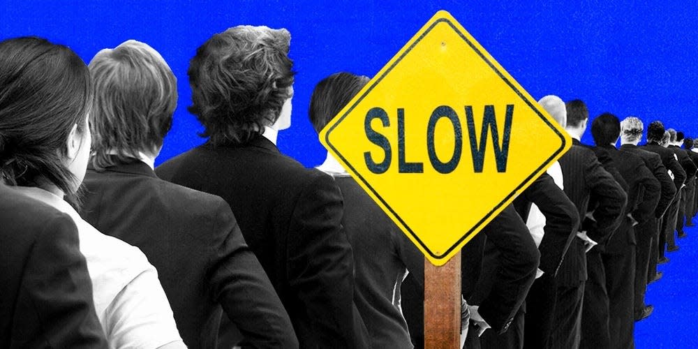 People standing in line near a street sign that says "slow"