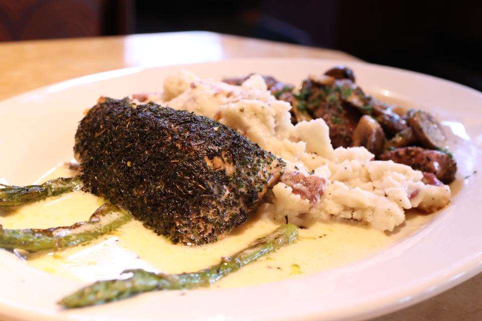 A steak diane on plate with green sauce next to herb-encrusted salmon at The Cheesecake Factory.