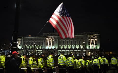 A supporter of Donald Trump waves the US flag outside Buckingham Palace  - Credit: Alberto Pezzali&nbsp;/AP