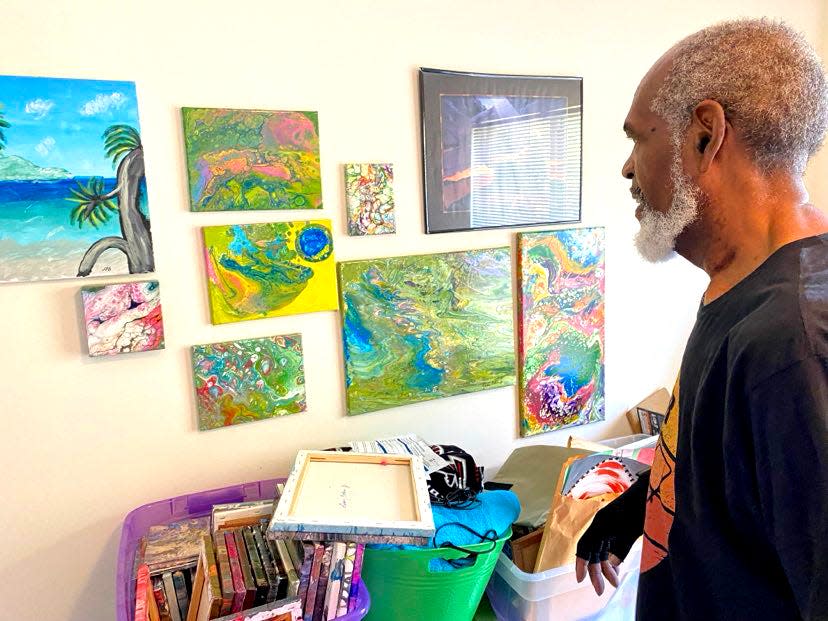 Leroy Bolden shows of some of the literally hundreds of paintings he has stored in a guest room at his home.