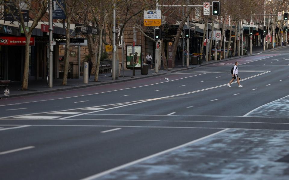 A lone man wearing a protective face mask crosses an empty street during a lockdown to curb the spread of a coronavirus disease (COVID-19) outbreak in Sydney, Australia, July 22, 2021. - Reuters