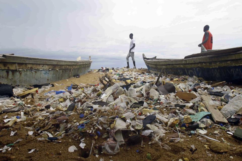 FILE - People walk on the plastic littered Port Bouet beach outside Abidjan, Ivory Coast, June 2, 2023. (AP Photo/Diomande Ble Blonde, File)