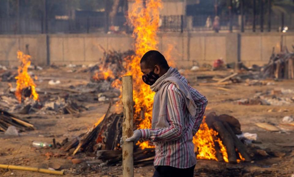 A man walks past burning funeral pyres in India.