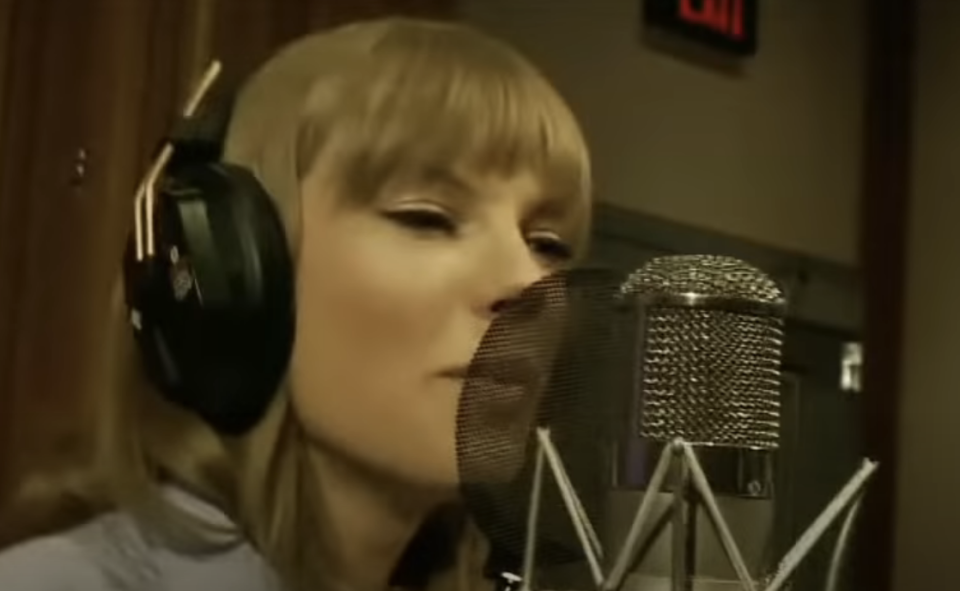 Woman singing into a microphone in a recording studio