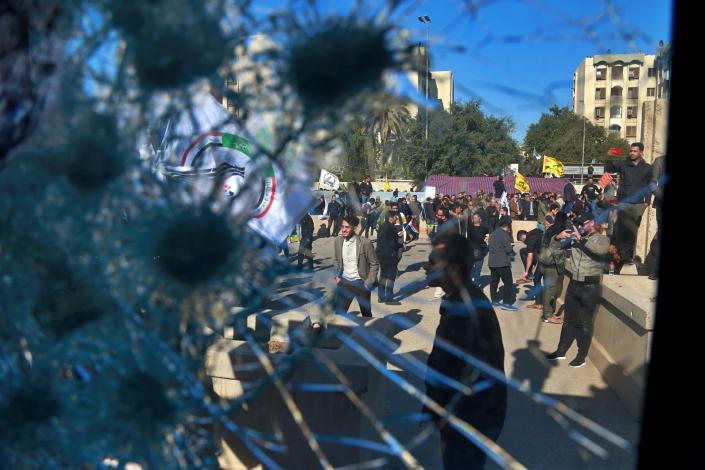 Shiite militia supporters are seen through a broken window of a checkpoint belonging to U.S. embassy, in front of the U.S. embassy, in Baghdad, Iraq, Tuesday, Dec. 31, 2019. (Photo: Khalid Mohammed/AP)