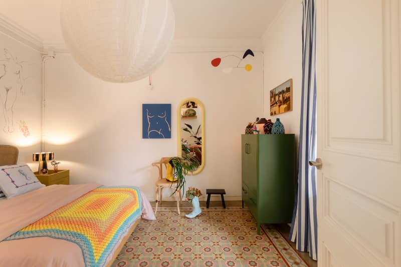 View of bedroom with colorful blanket and floor.