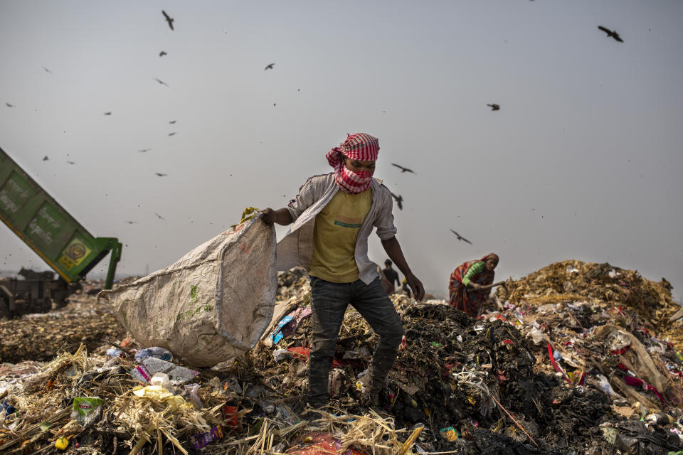 Trash workers look for recyclables at Bhalswa landfill on the outskirts of New Delhi, India, Wednesday, March 10, 2021. An estimated 20 million people around the world help keep cities clean by scavenging through landfills and dumps. Experts say these trash pickers, who sometimes toil alongside paid municipal sanitation workers, provide a vital service, yet they usually are not on a priority list for coronavirus vaccines. (AP Photo/Altaf Qadri)