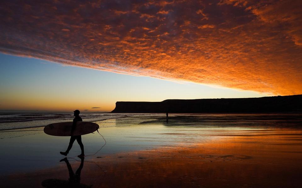 A surfer enjoys a spectacular sunset this afternoon - Getty
