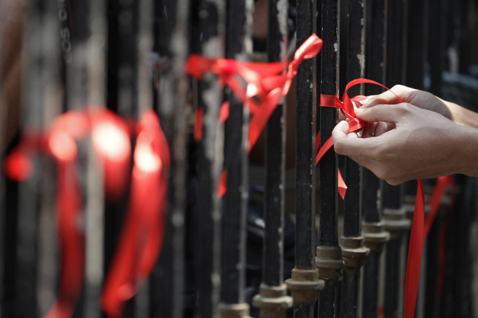 Demonstrators tie red ribbons to symbolize their protest against the early release of U.S. Marine Lance Cpl. Joseph Scott Pemberton during a rally outside the Department of Justice in Manila, Philippines, Thursday, Sept. 3, 2020. A Philippine court has ordered the early release for good conduct of Pemberton who was convicted in the 2014 killing of transgender Filipino Jennifer Laude which sparked anger in the former American colony. (AP Photo/Aaron Favila)