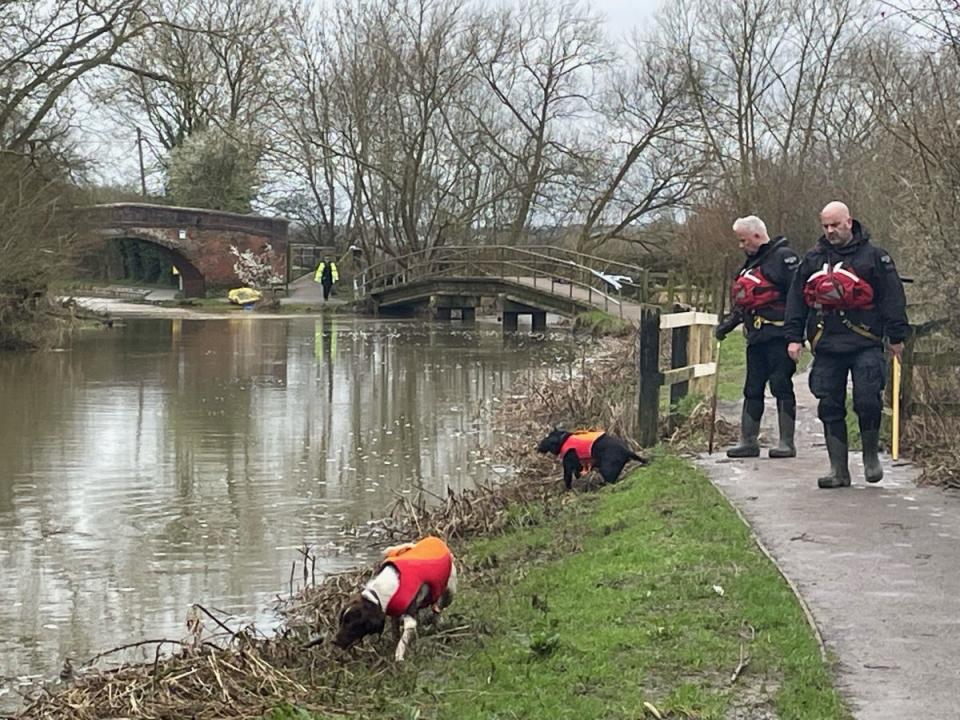 Dogs look for a sign of Xielo on the banks of a canal (Jacob King/PA Wire)