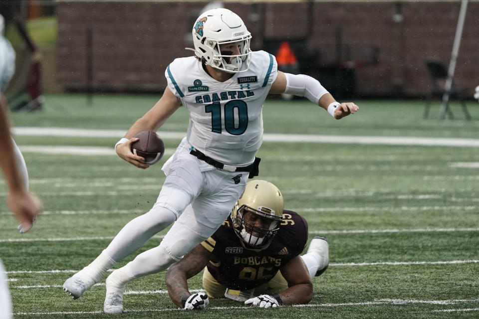 Coastal Carolina's Grayson McCall (10) runs past Texas State's Nico Ezidore (95) during the first half of an NCAA college football game in San Marcos, Texas, Saturday, Nov. 28, 2020. (AP Photo/Chuck Burton)