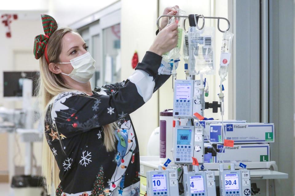 ICU charge nurse Beth Koelliker checks intravenous pumps delivering medications to COVID patient