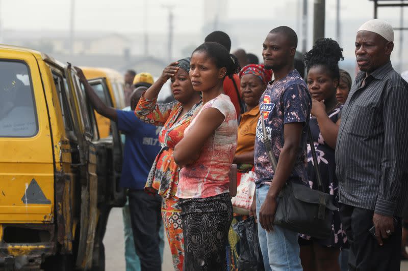 People are seen waiting for a bus at a bus-stop in Lagos