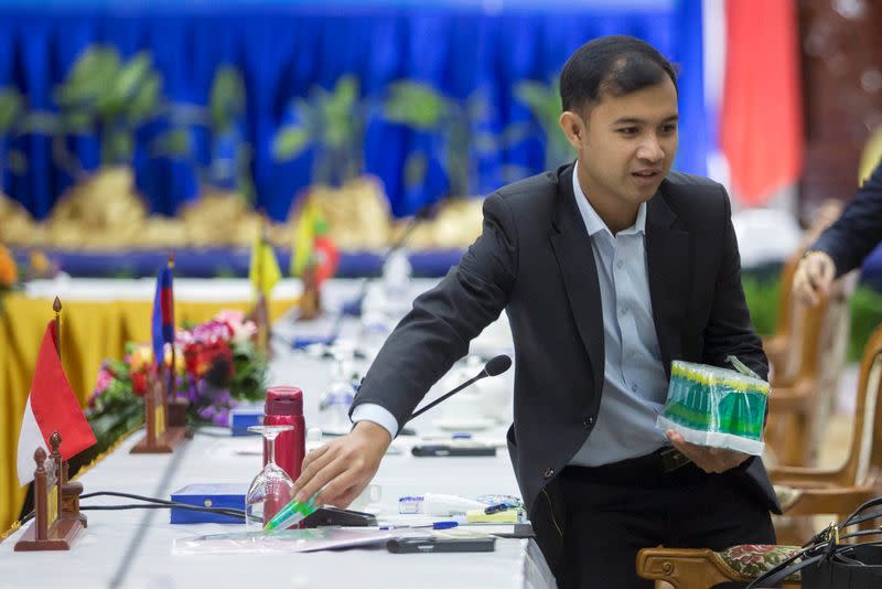 Laos foreign minister worker places alcohol gel tubes on table before meeting with ASEAN foreign ministers and China on coronavirus outbreak in Vientiane