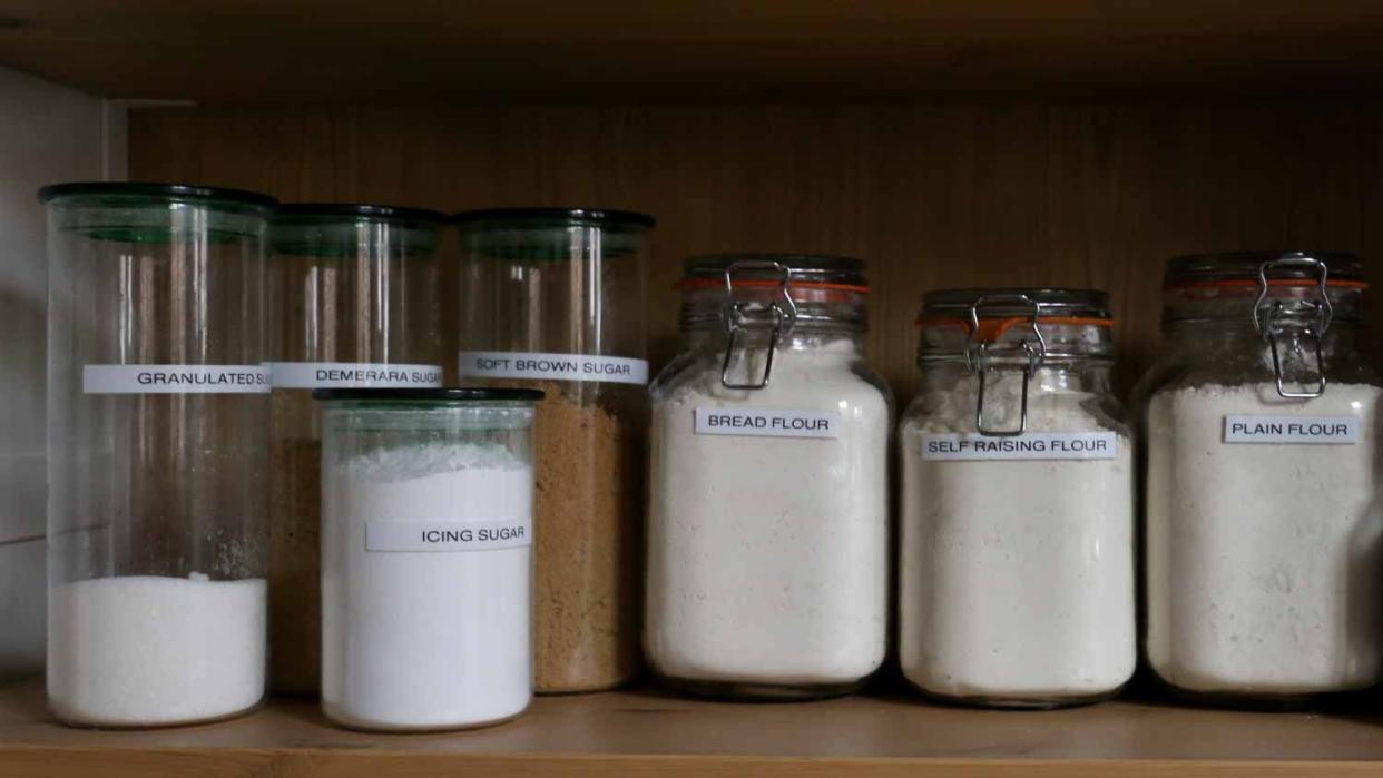 Jars of flour and sugar on a wooden shelf