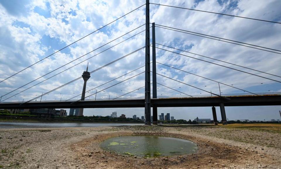 An inland vessel navigates on the Rhine as the partially dried-up river bed is seen in the foreground in Düsseldorf, western Germany.