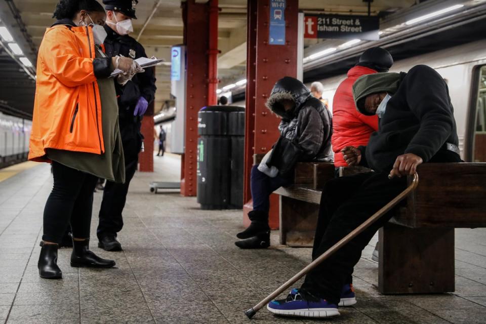 A homeless outreach worker and New York police officer assist people on a subway platform in 2020. (AP)