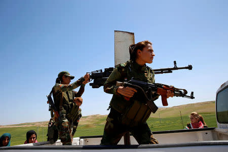 Yazidi female fighter Asema Dahir (L), 21, holds a weapon as she rides a pickup truck during a deployment near the frontline of the fight against Islamic State militants in Nawaran near Mosul, Iraq, April 20, 2016. REUTERS/Ahmed Jadallah