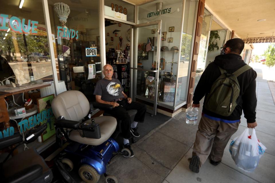 Larrie Long waits for customers in front of Thrift and Treasures in the historic downtown of Atwater