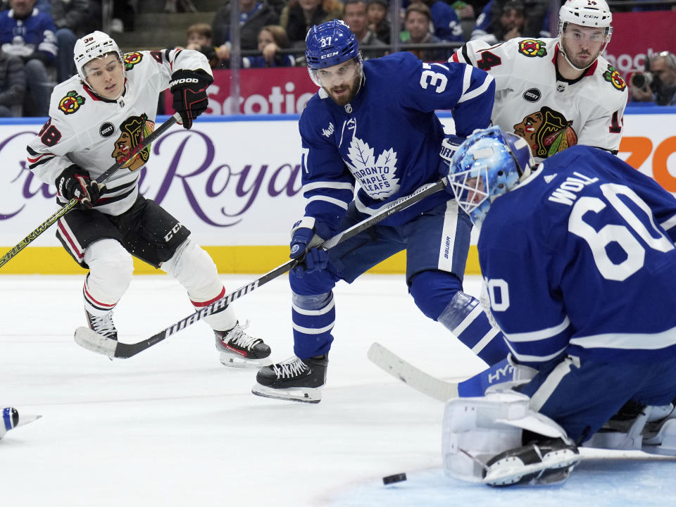 Chicago Blackhawks center Connor Bedard (98) shoots against Toronto Maple Leafs goaltender Joseph Woll (60) as Leafs' Timothy Liljegren (37) and Blackhawks' Boris Katchouk (14) look on during third-period NHL hockey game action in Toronto, Monday, Oct. 16, 2023. (Nathan Denette/The Canadian Press via AP)