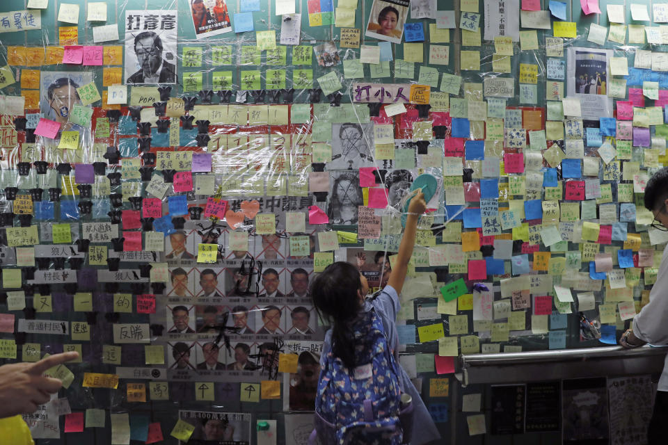 In this photo taken Friday, July 12, 2019, a child reaches out to post-it notes on the city's version of the Lennon Wall in Hong Kong. Hong Kong activists first created their own Lennon Wall during the 2014 protests, covering a wall with a vibrant Post-it notes calling for democratic reform. This time, they have taken to sticking the neon-colored notes everywhere, erecting impromptu Lennon Walls across the city as quickly as others might tear them down. Some protesters have called it "flowers blossoming everywhere." (AP Photo/Kin Cheung)