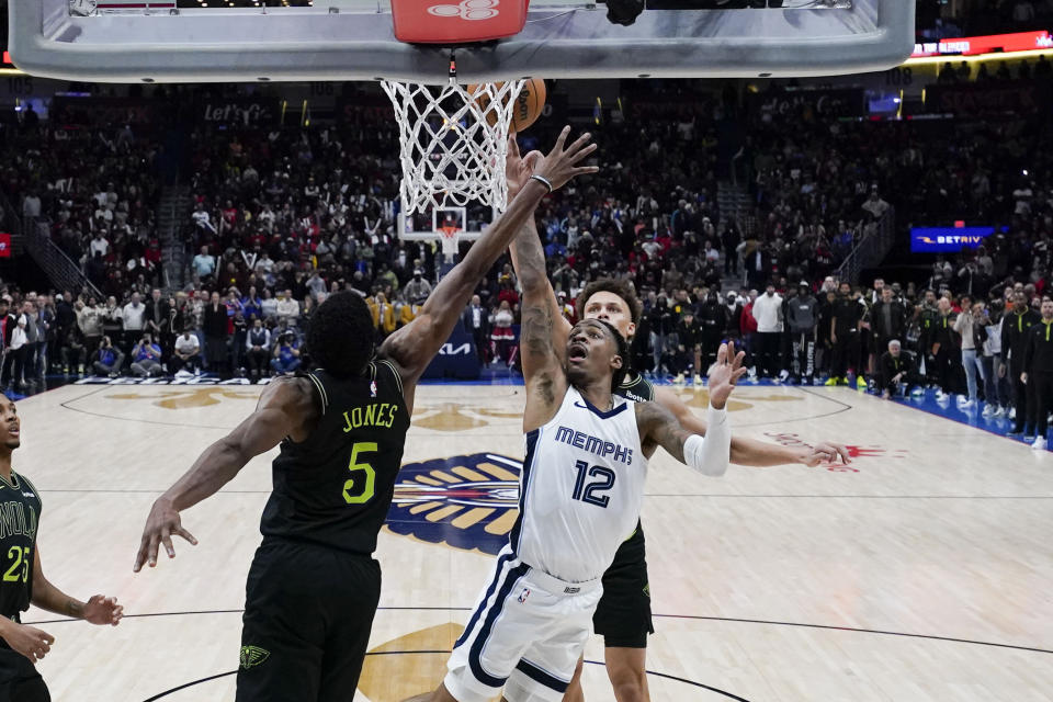 Memphis Grizzlies guard Ja Morant (12) goes to the basket between New Orleans Pelicans forward Herbert Jones (5) and guard Dyson Daniels for the game winning shot at the buzzer in the second half of an NBA basketball game in New Orleans, Tuesday, Dec. 19, 2023. The Grizzlies won 115-113. (AP Photo/Gerald Herbert)