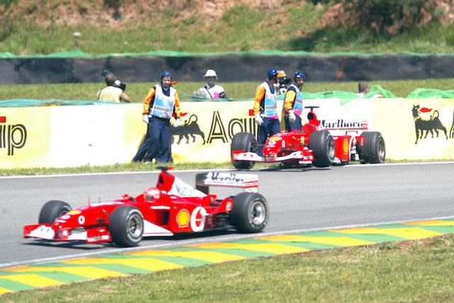 The new Ferrari F2002 of Michael Schumacher passes team mate Rubens Barrichello's stricken old Ferrari F2001 out on the circuit as Schumacher decision to try out the new car seems to have worked