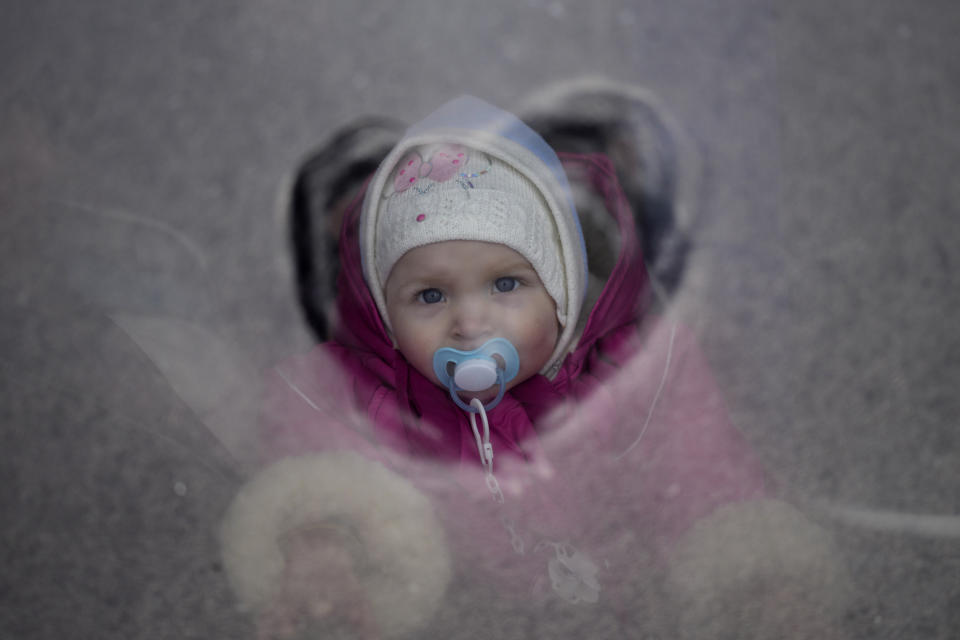 A child who fled the war from neighboring Ukraine looks through a bus window in Przemysl, Poland, Wednesday, March 9, 2022. (AP Photo/Daniel Cole)