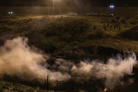 Migrants run as tear gas is thrown by U.S. Border Protection officers to the Mexican side of the border fence after they climbed the fence to get to San Diego, Calif., from Tijuana, Mexico, Tuesday, Jan. 1, 2019. Discouraged by the long wait to apply for asylum through official ports of entry, many migrants from recent caravans are choosing to cross the U.S. border wall and hand themselves in to border patrol agents. (AP Photo/Daniel Ochoa de Olza)