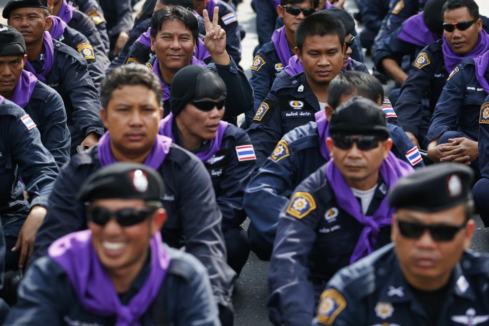 Policemen share a light moment as anti-government protesters enter the compound of the metropolitan police headquarters, the site of fierce clashes over the last few days in Bangkok December 3, 2013. Thailand's government ordered police to stand down and allow protesters into state buildings on Tuesday, removing a flashpoint for clashes and effectively bringing an end to days of violence in Bangkok in which five people have died. REUTERS/Damir Sagolj (THAILAND - Tags: POLITICS CIVIL UNREST)