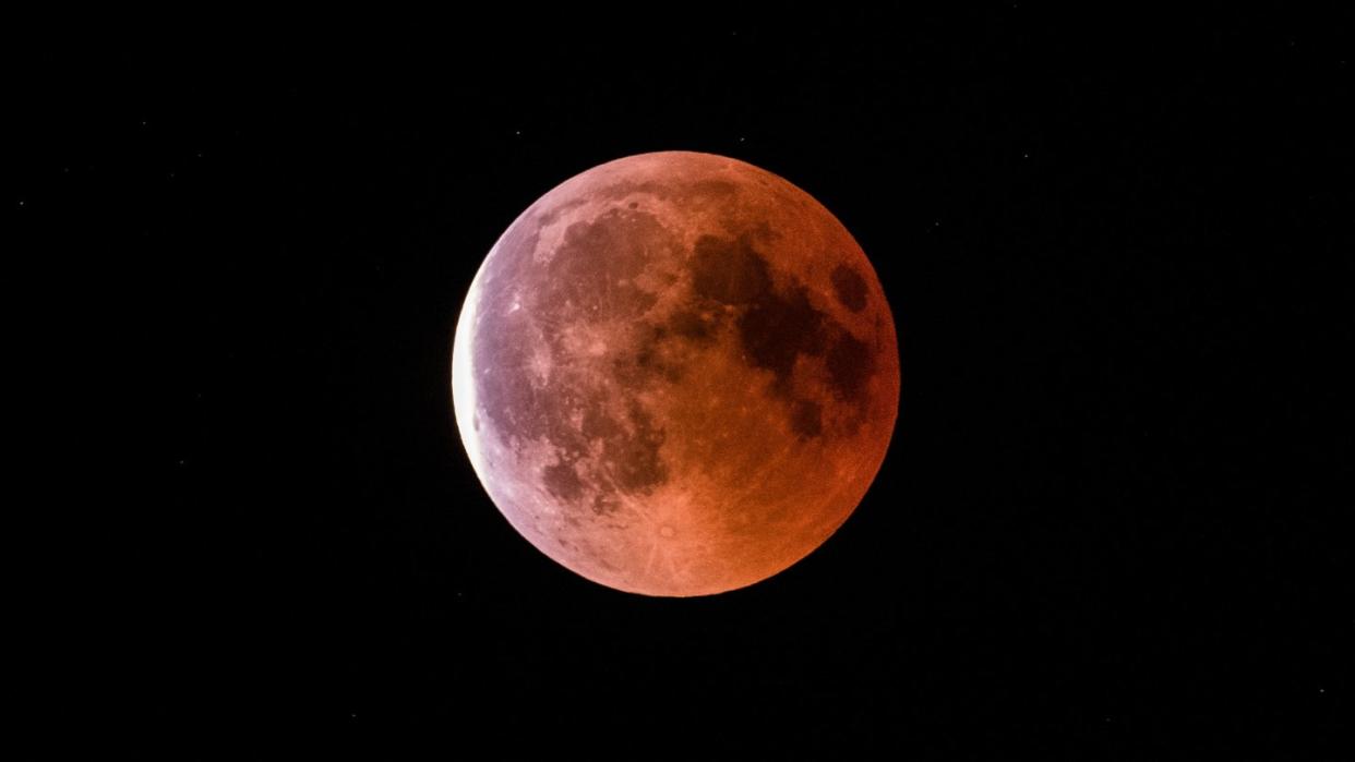 Der teilweise vom Erdschatten verdunkelte Vollmond leuchtet während einer Mondfinsternis rot bis orange. Foto: Silas Stein/Archiv