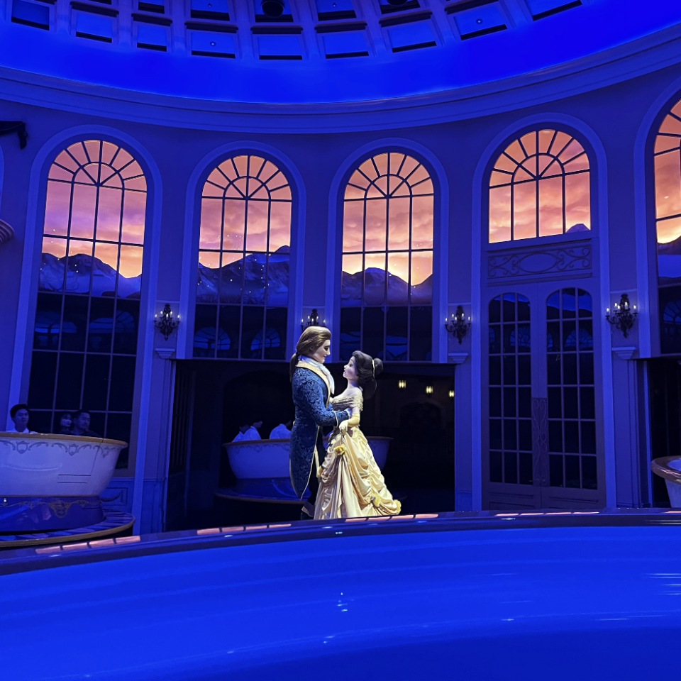 Belle and Beast from Beauty and the Beast dance in an ornate room with large windows and a domed ceiling