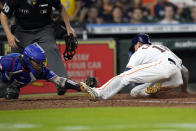 Houston Astros' Jason Castro, right, scores on a wild pitch as Texas Rangers catcher Jonah Heim tries to tag him during the fifth inning of a baseball game Saturday, May 21, 2022, in Houston. (AP Photo/David J. Phillip)