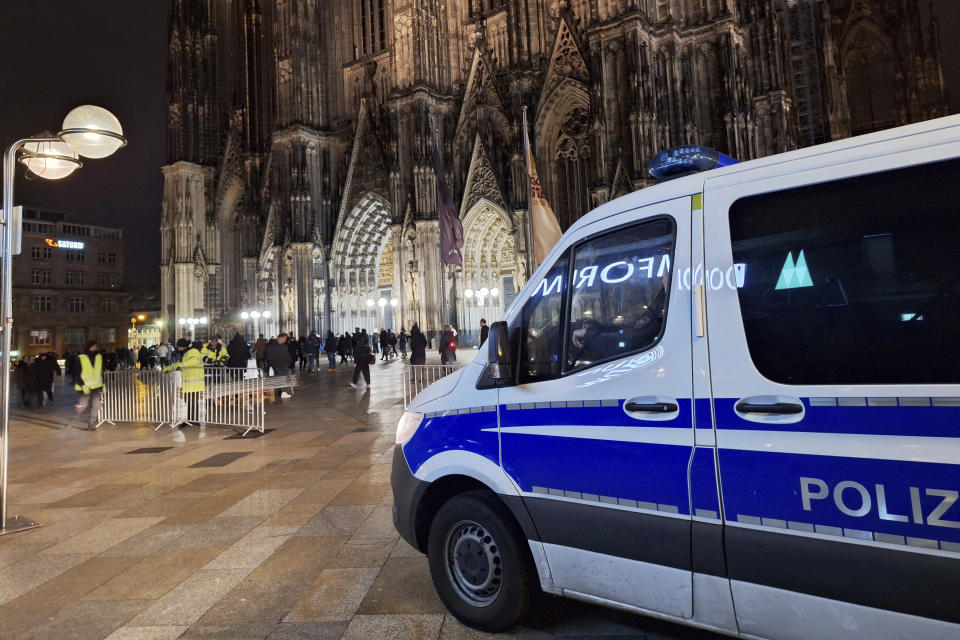 A police vehicle is parked in front of the cathedral in Cologne, Germany, Saturday, Dec. 23, 2023. Cologne police acting on indications of a possible attack searched Germany's landmark cathedral with sniffer dogs Saturday and said worshippers attending Christmas Eve Mass would undergo security screening before being allowed in. (Sascha Thelen/dpa via AP)