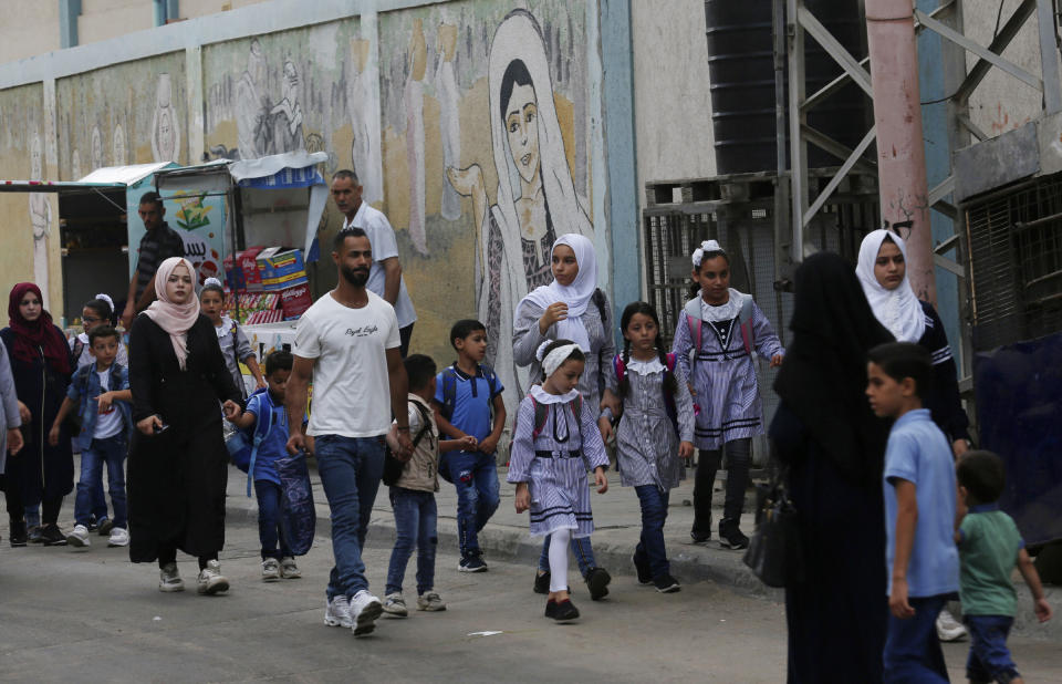 Women bring their children to the United-Nation run Elementary School on the first day of the new school year at the Shati refugee camp in Gaza City, Saturday, Aug. 8, 2020. Schools run by both Palestinian government and the U.N. Refugee and Works Agency (UNRWA) have opened almost normally in the Gaza Strip after five months in which no cases of community transmission of the coronavirus had been recorded. (AP Photo/Adel Hana)